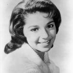 A young white woman with dark brown hair in a posed studio headshot