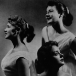 Three young white women wearing matching dresses in a posed studio shot.