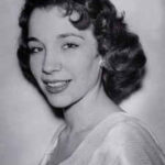 A young white woman with dark curly hair in a 3/4 pose formal headshot